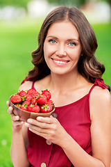 Image showing happy woman eating strawberry at summer park