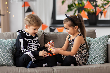 Image showing kids in halloween costumes with candies at home