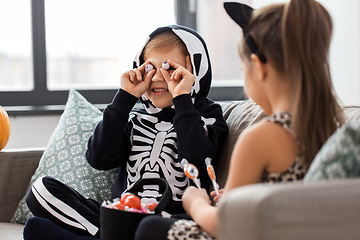 Image showing kids in halloween costumes with candies at home