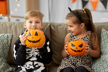 Image showing kids in halloween costumes with pumpkins at home