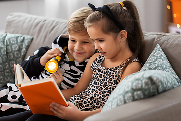 Image showing kids in halloween costumes reading book at home