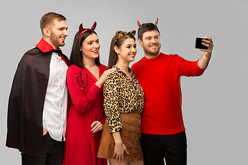 Image showing happy friends in halloween costumes taking selfie