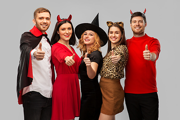 Image showing happy friends in halloween costumes snow thumbs up