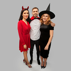 Image showing happy friends in halloween costumes over grey