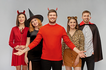 Image showing happy friends in halloween costumes over grey