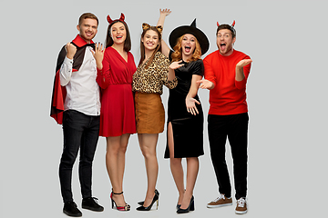 Image showing happy friends in halloween costumes over grey