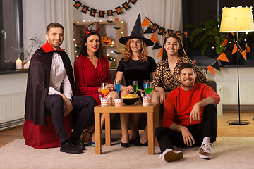 Image showing happy friends in halloween costumes at home party