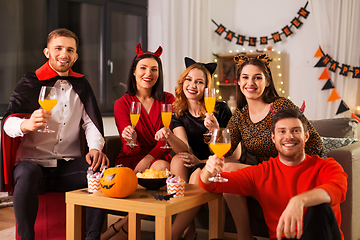 Image showing happy friends in halloween costumes at home party