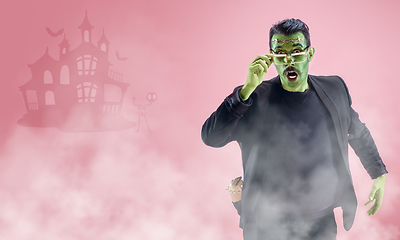 Image showing Young man as a zombie on pink background, halloween time, flyer with copyspace