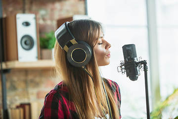 Image showing Woman in headphones recording music, singing or making broadcast internet tutorial while sitting in loft workplace or at home