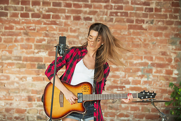 Image showing Woman in headphones recording music, singing or making broadcast internet tutorial while sitting in loft workplace or at home