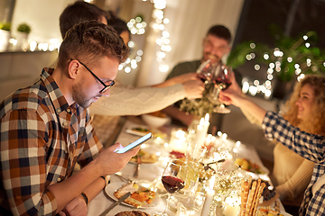 Image showing man with smartphone at dinner party with friends