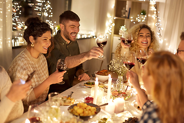 Image showing happy friends drinking red wine at christmas party