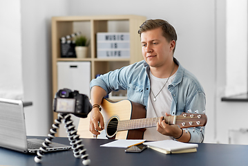 Image showing man or blogger with camera playing guitar at home