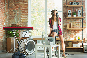 Image showing Woman in headphones recording music, singing or making broadcast internet tutorial while sitting in loft workplace or at home