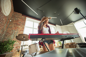 Image showing Woman recording music, singing and playing piano while standing in loft workplace or at home