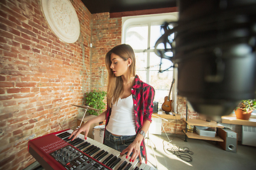 Image showing Woman recording music, singing and playing piano while standing in loft workplace or at home