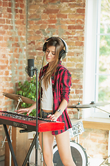 Image showing Woman recording music, singing and playing piano while standing in loft workplace or at home