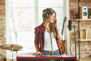 Image showing Woman recording music, singing and playing piano while standing in loft workplace or at home