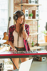 Image showing Woman recording music, singing and playing piano while standing in loft workplace or at home