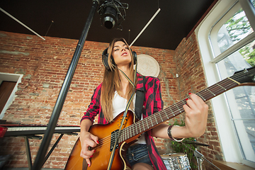 Image showing Woman in headphones recording music, singing or making broadcast internet tutorial while sitting in loft workplace or at home