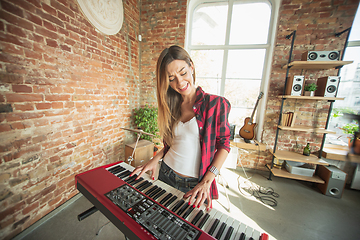 Image showing Woman recording music, singing and playing piano while standing in loft workplace or at home