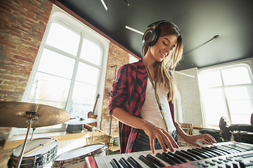 Image showing Woman recording music, singing and playing piano while standing in loft workplace or at home