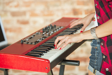 Image showing Woman recording music, singing and playing piano while standing in loft workplace or at home