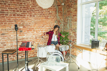 Image showing Woman recording music, singing and playing drums while sitting in loft workplace or at home