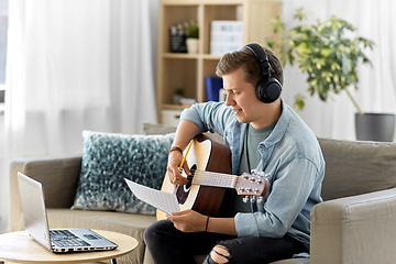 Image showing man in headphones with guitar, notes and laptop