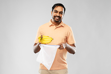 Image showing happy man putting bananas into reusable string bag