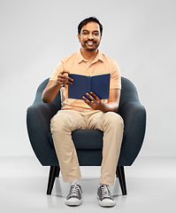 Image showing happy young indian man reading book in chair