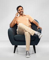 Image showing happy indian man calling on smartphone in chair