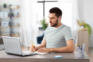 Image showing man with notebook, earphones and laptop at home