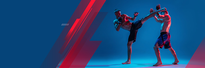 Image showing MMA. Two professional fighters punching or boxing isolated on blue studio background in neon