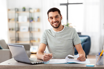 Image showing man with papers and laptop working at home office