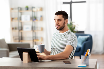 Image showing man with tablet pc drinking coffee at home office