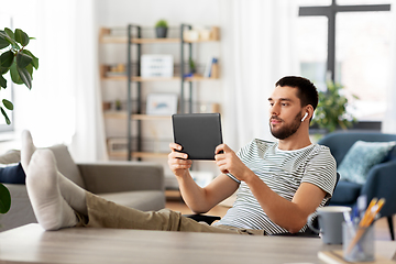 Image showing man with tablet pc and earphones at home