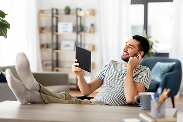 Image showing happy man with tablet pc and earphones at home