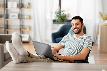 Image showing man with laptop resting feet on table at home