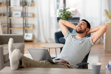 Image showing happy man with laptop resting at home office