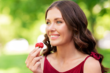 Image showing happy woman eating strawberry at summer park