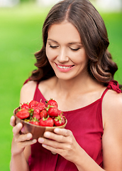 Image showing happy woman eating strawberry at summer park