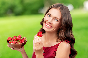 Image showing happy woman eating strawberry at summer park