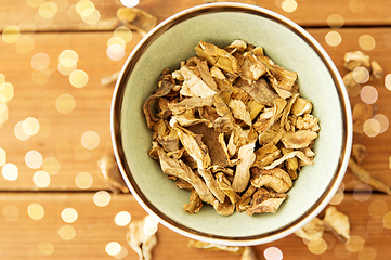 Image showing dried mushrooms in bowl on wooden background