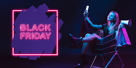 Image showing Portrait of young woman in neon light on dark backgound. The human emotions, black friday, cyber monday, purchases, sales, finance concept. Neoned lettering.