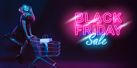 Image showing Portrait of young woman in neon light on dark backgound. The human emotions, black friday, cyber monday, purchases, sales, finance concept. Neoned lettering.