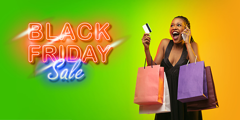 Image showing Portrait of young woman in neon light on gradient backgound. The human emotions, black friday, cyber monday, purchases, sales, finance concept. Neoned lettering.