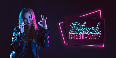 Image showing Portrait of young woman in neon light on dark backgound. The human emotions, black friday, cyber monday, purchases, sales, finance concept. Neoned lettering.