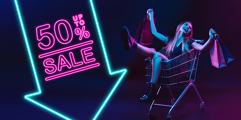 Image showing Portrait of young woman in neon light on dark backgound. The human emotions, black friday, cyber monday, purchases, sales, finance concept. Neoned lettering.